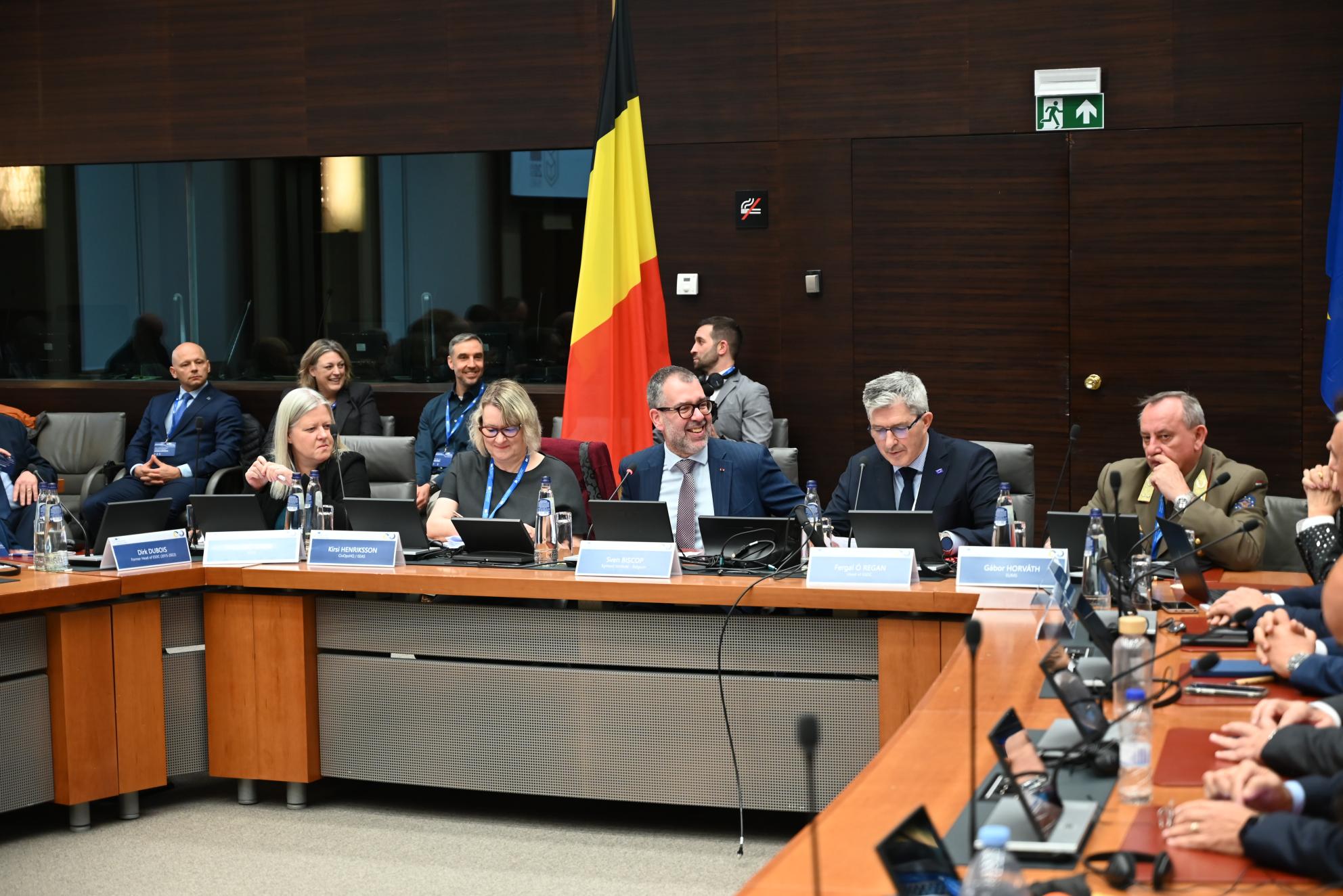 A panel with 3 men and three woman. Flag of Belgium in the background. 