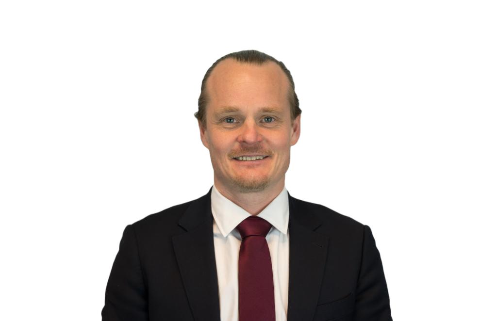Isak Enstrom in a dark suit, red tie, smiling
