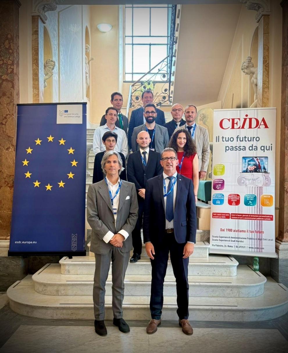 Family picture of course participants. 12 Participants. Left ESDC roll-up, right CEIDA roll-up. Participants are standing on stairs of an older italian building. Participants are formally dressed.
