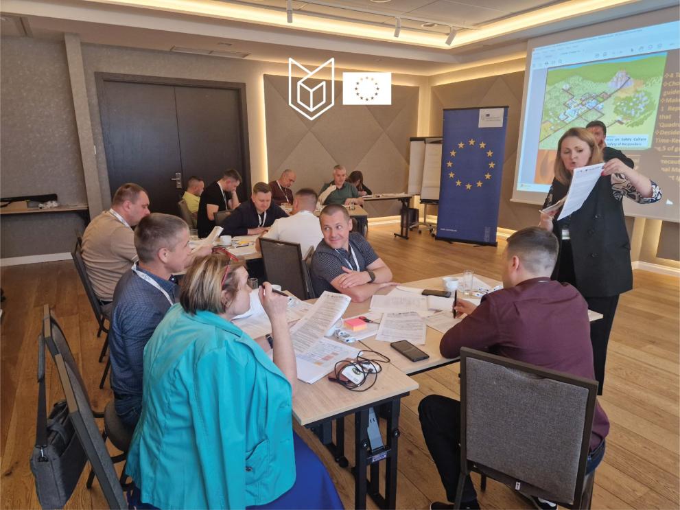 Group of participants around a table discussing. EU roll-up in the background.