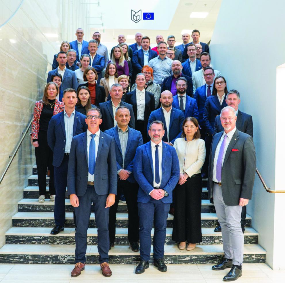 Group picture of the participants standing on stairs. Most in suit or formal dress. ESDC logo on top of the picture.