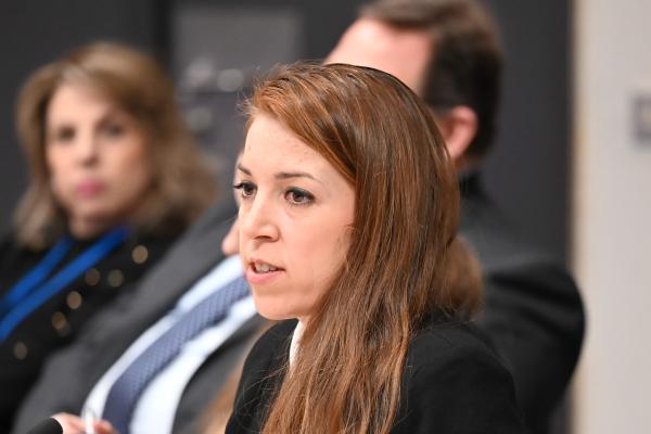 Dr Neli Kirilova speaking in a conference setting, dark blue blazer