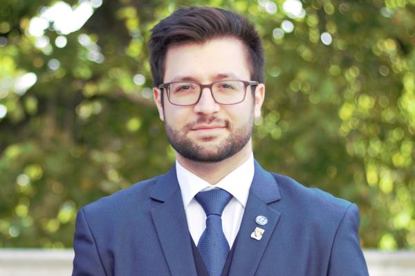 Dr Petri Petrikkos in a blue suit and blue tie. Tree in the background.
