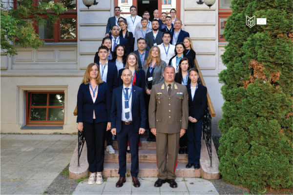 Group Picture of ca. 20 people on stairs. All formally dressed. Man in uniform in front. Bushes on the right.