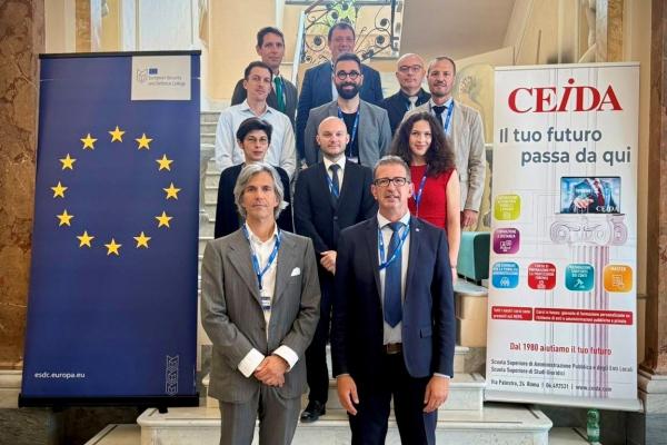 Family picture of course participants. 12 Participants. Left ESDC roll-up, right CEIDA roll-up. Participants are standing on stairs of an older italian building. Participants are formally dressed.