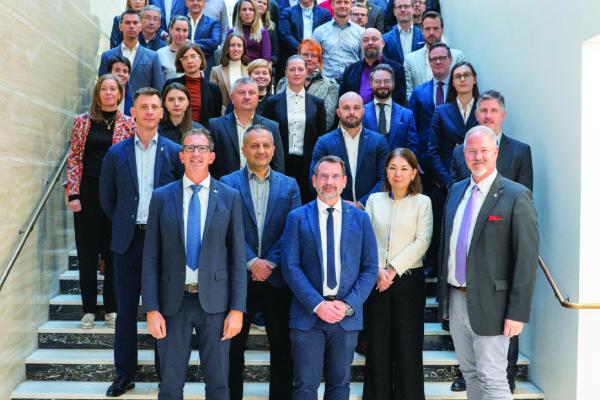 Group picture of the participants standing on stairs. Most in suit or formal dress. ESDC logo on top of the picture.