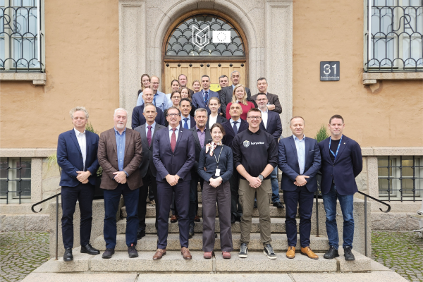 Group of participants wearing mostly formal wear in front of the Swedish Defence University
